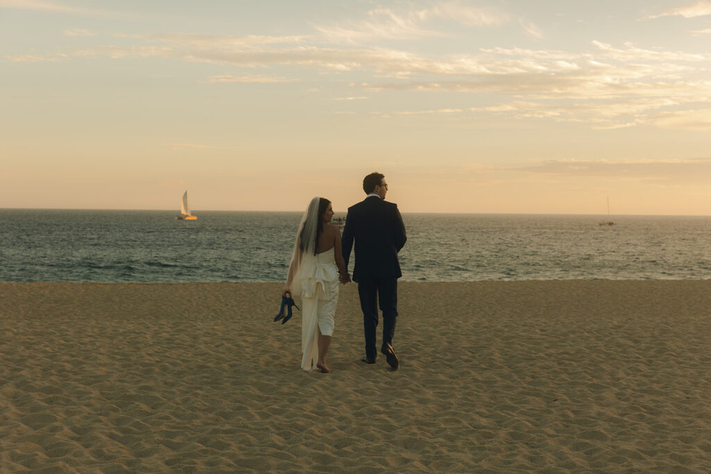 couple walks across beach at Mexico sunset destination wedding