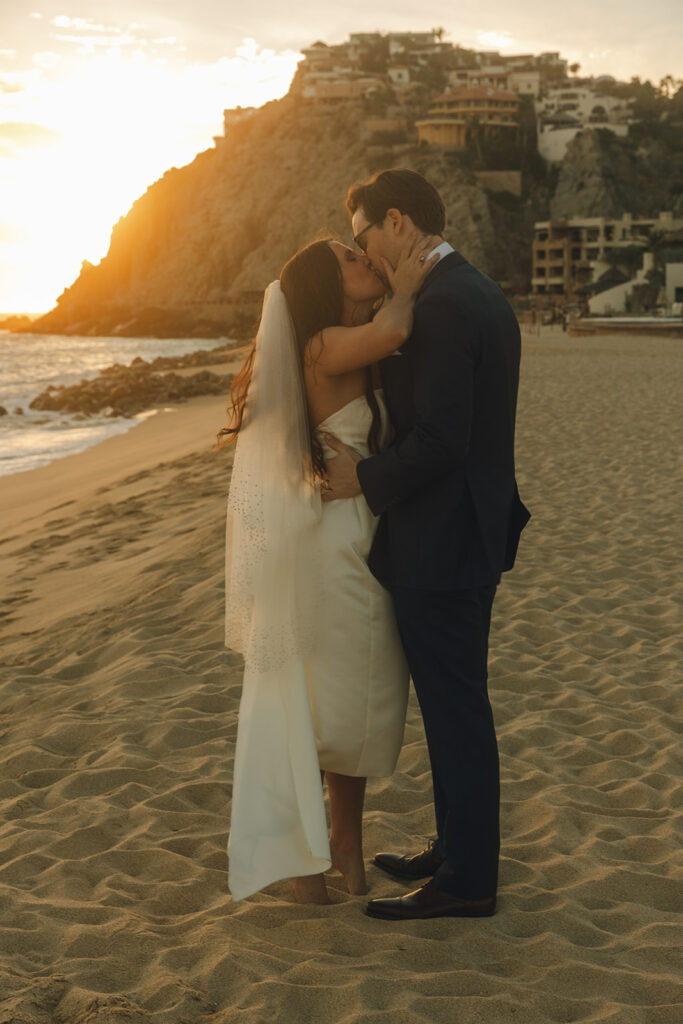 couple kisses on beach at Mexico sunset destination wedding