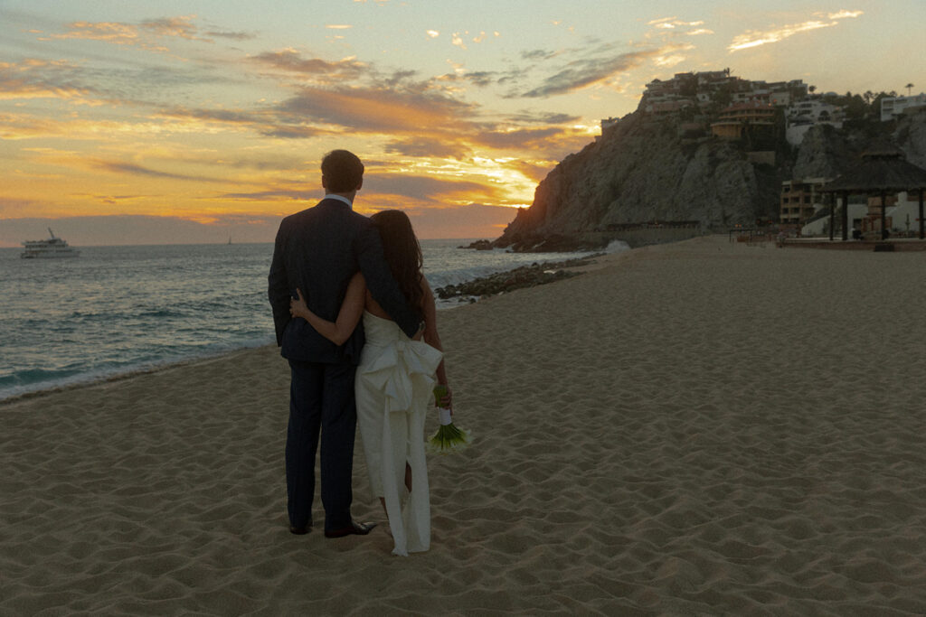 couple embraces on beach at Mexico sunset destination wedding