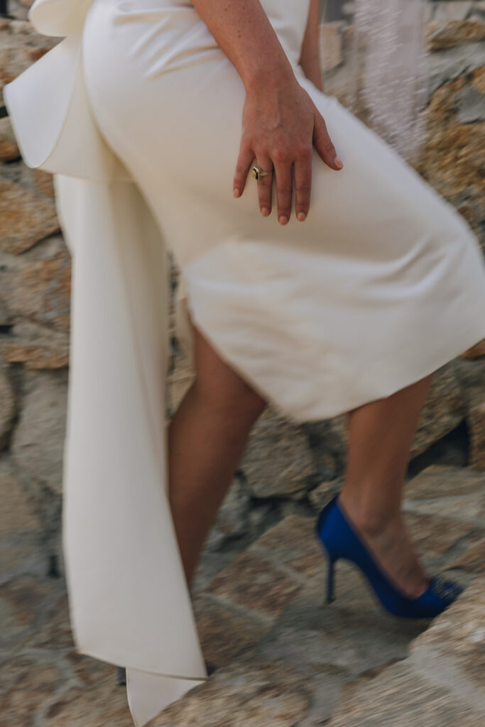 bride walks wearing blue shoes in wedding dress with large bow on back