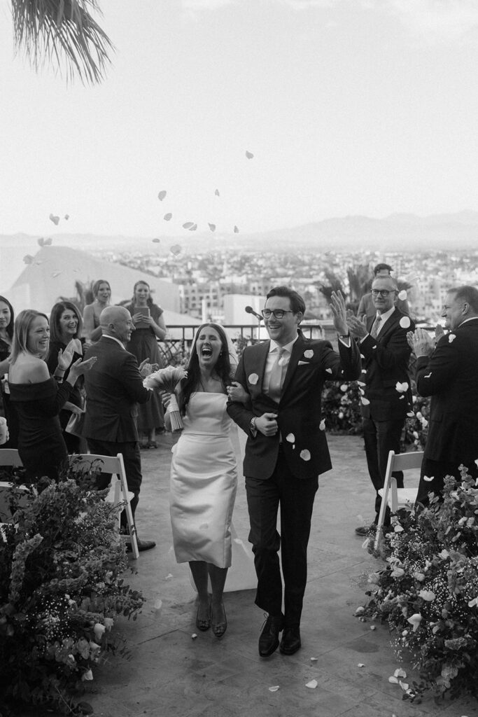 couple exits wedding with flower petals thrown at them
