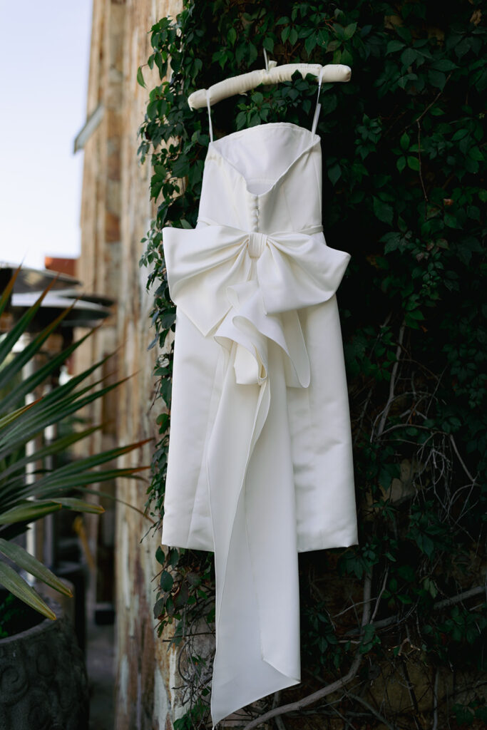 wedding dress hangs with large bow on back