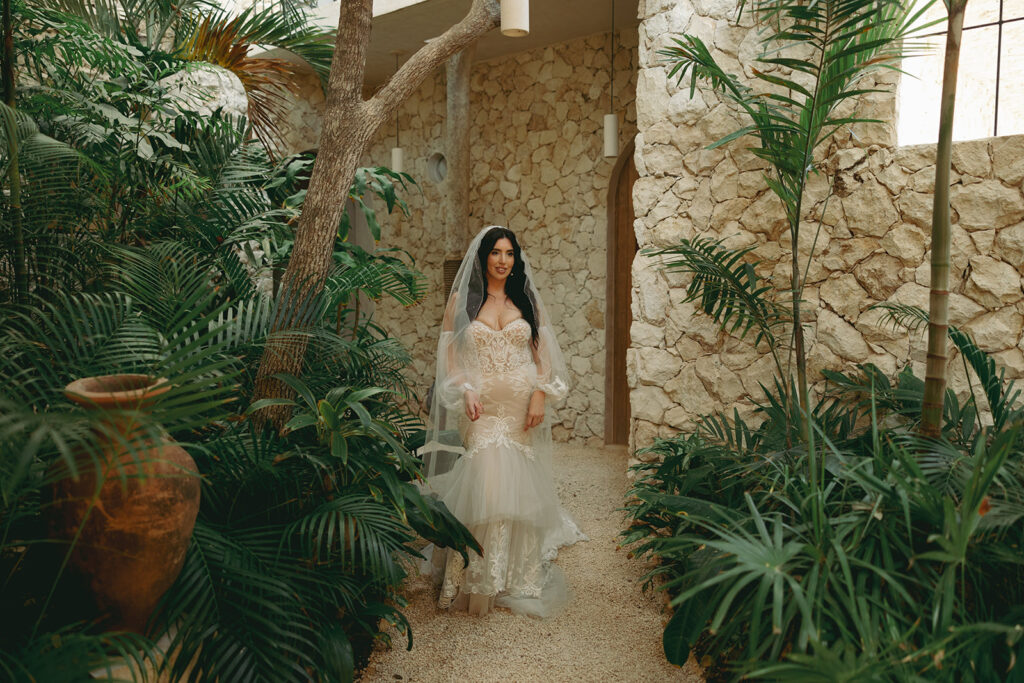 bride walks along pathway surrounded by green ferns