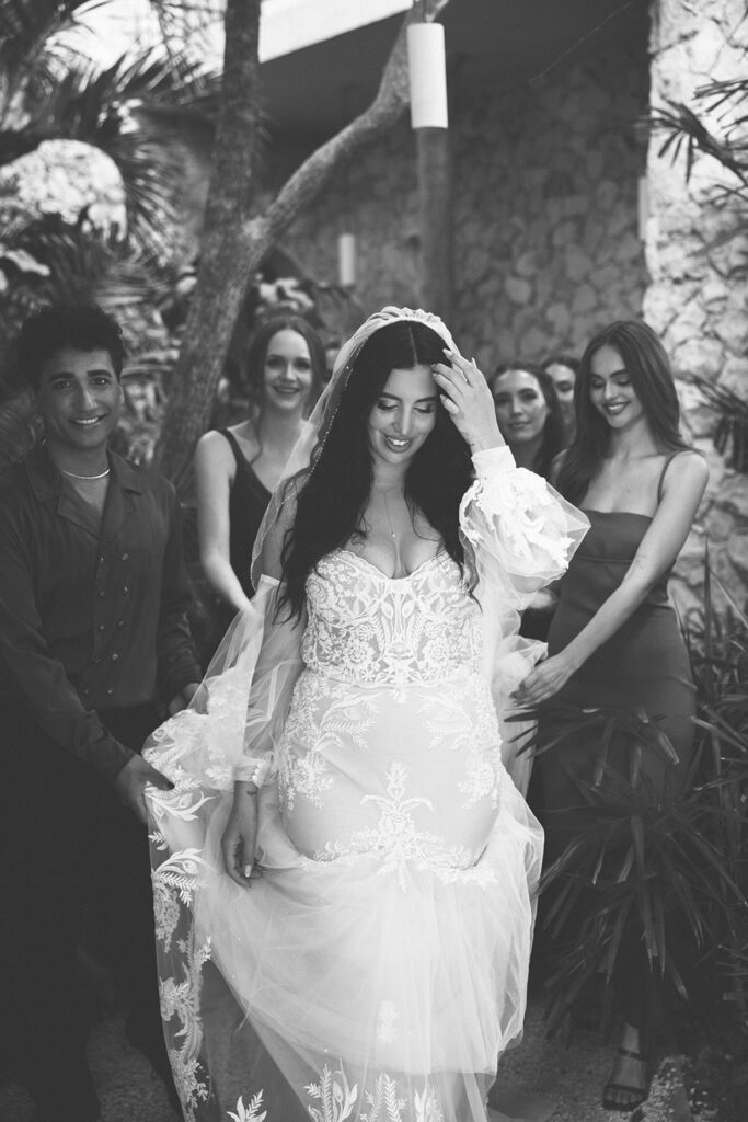 bride walks along wedding party holding up her dress