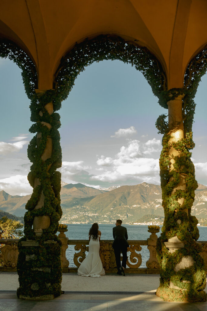 couple leans on railing looking at Lake Como wedding in Italy