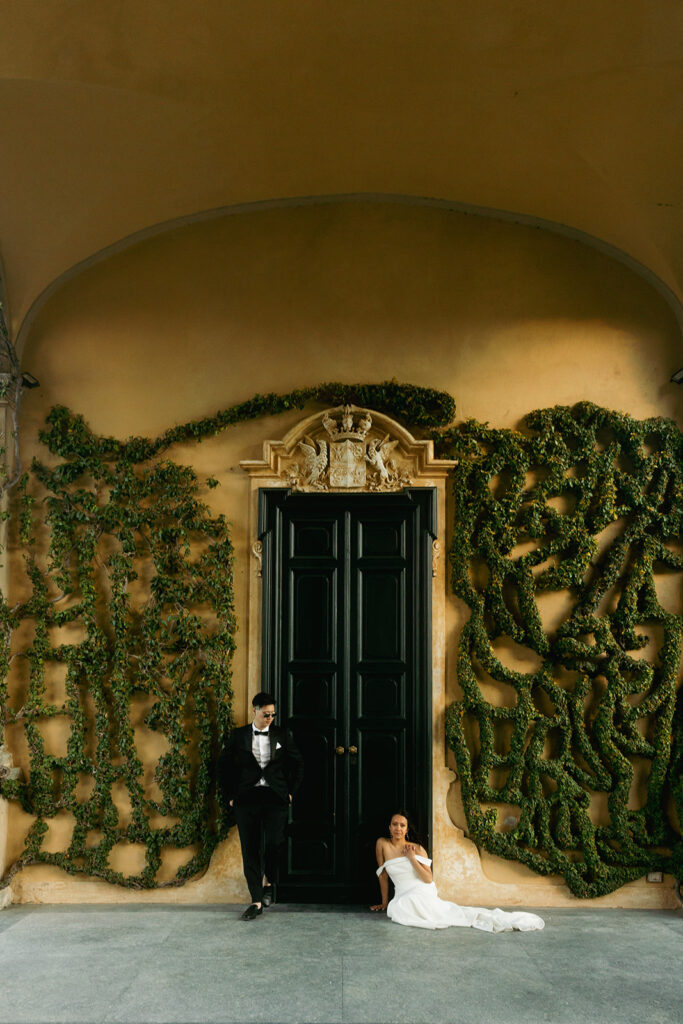 couple sits in front of large door at Italy Lake Como wedding 