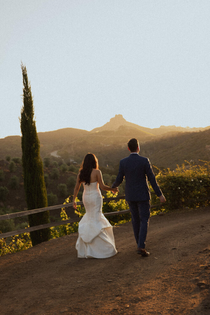 couple walks along valley filled with sunset light photographed by traveling photographers