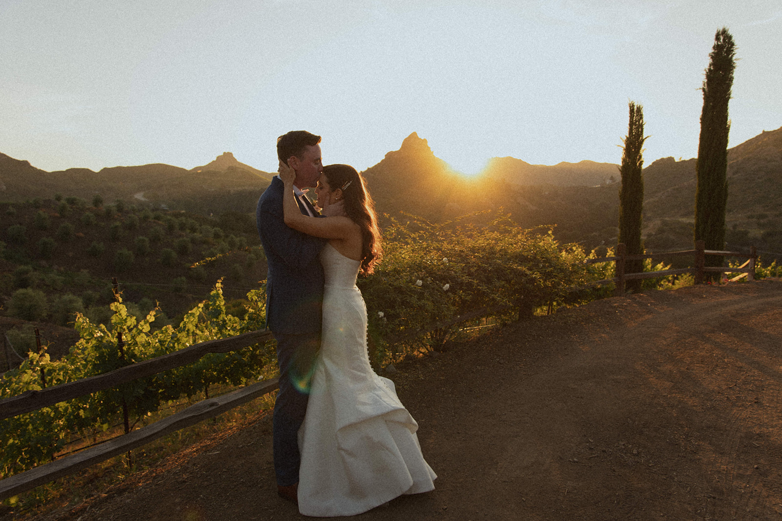 wedding couple kisses as sun sets behind mountain