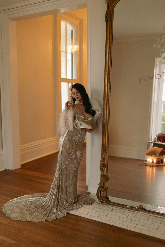 boudoir bride stands holding vintage phone in front of mirror