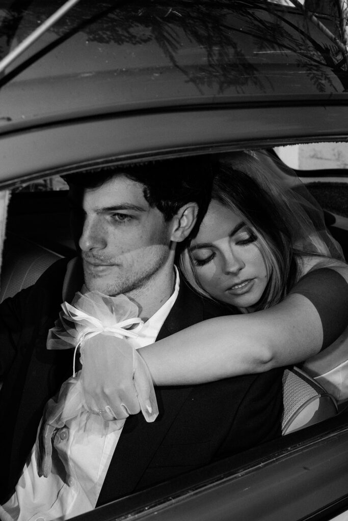 couple embraces in vintage getaway car at classy wedding 