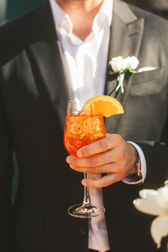 groom holds cocktail at reception