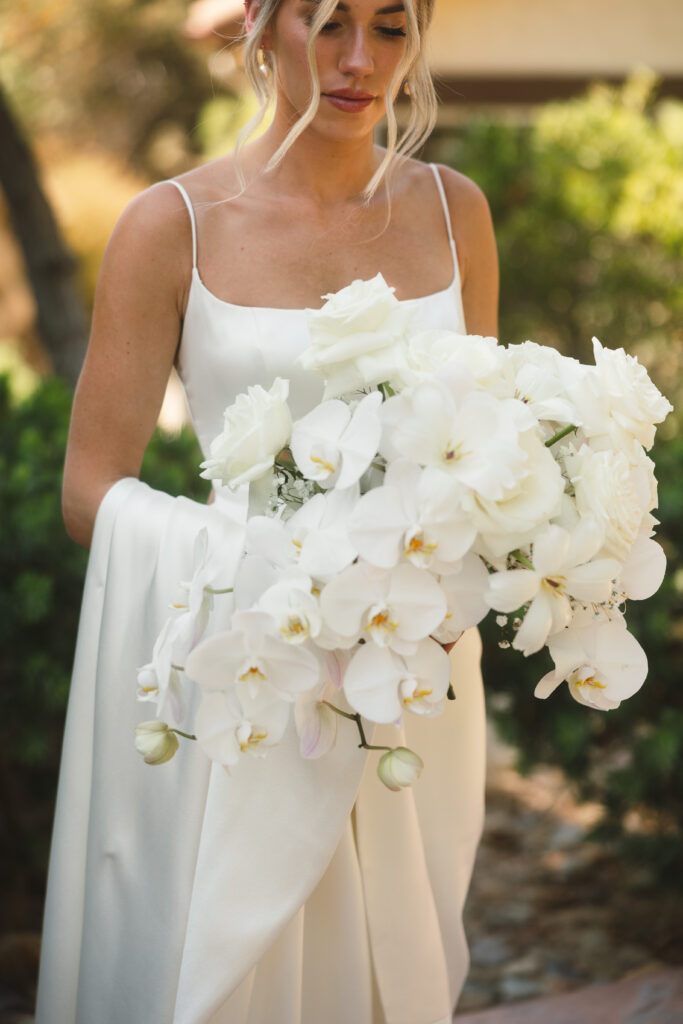 bride looking down at all white bouquet 