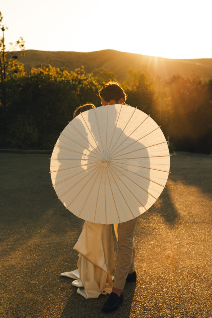 bride and groom holding a parasol that creates a silhouette with the shadow 