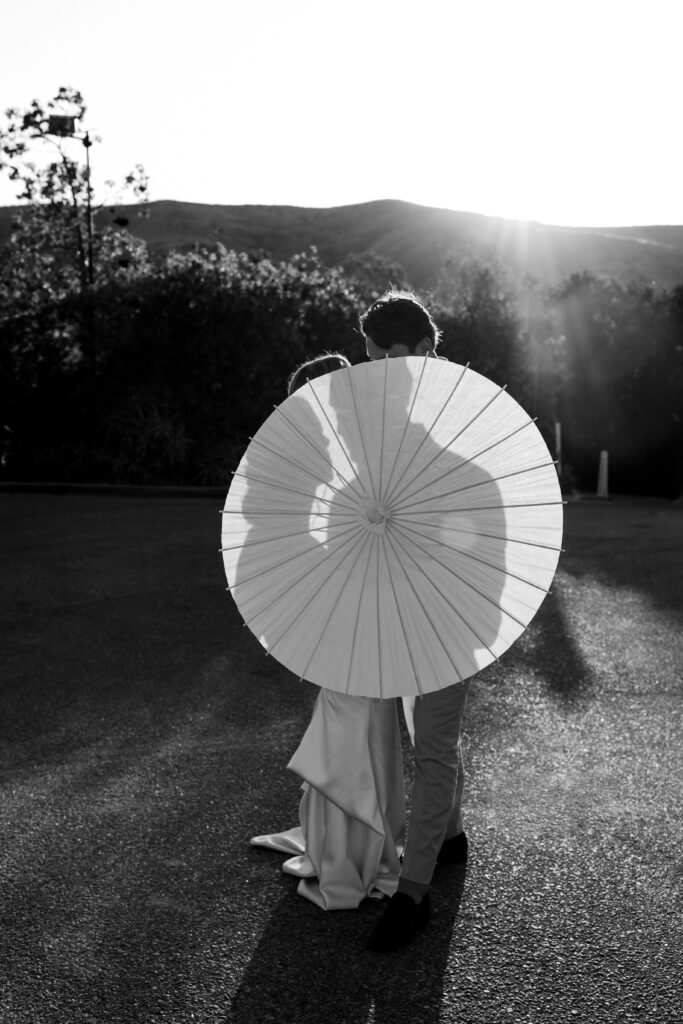 bride and groom holding a parasol that creates a silhouette with the shadow 