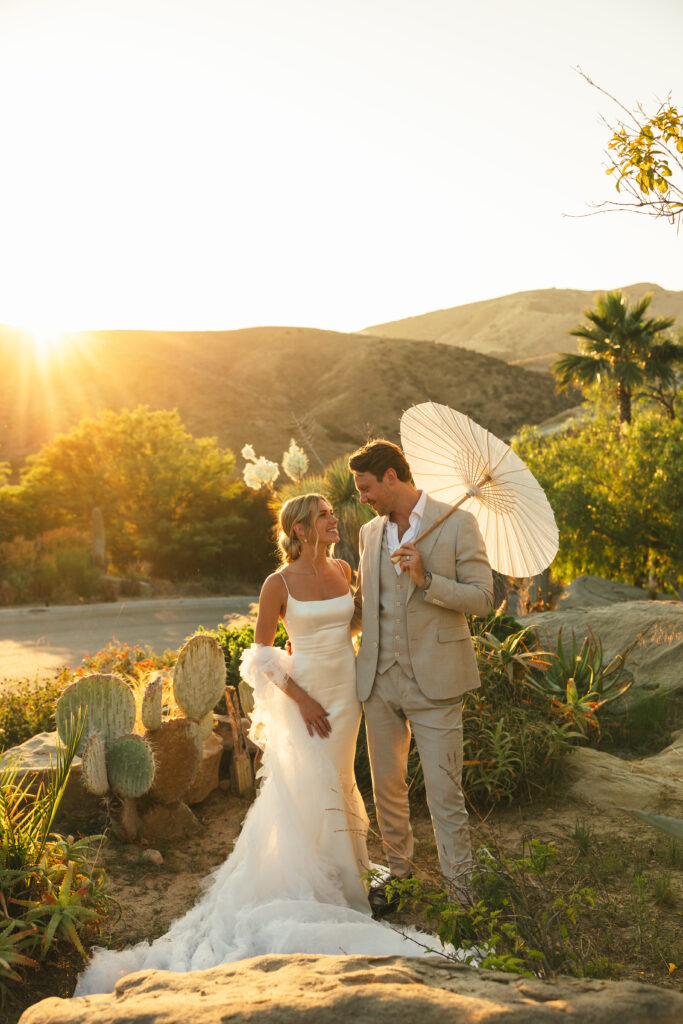 couple holds hands at sunset outdoor summer wedding