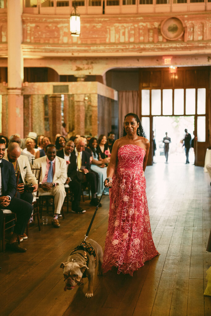 mother of bride walks dog down aisle at wedding 