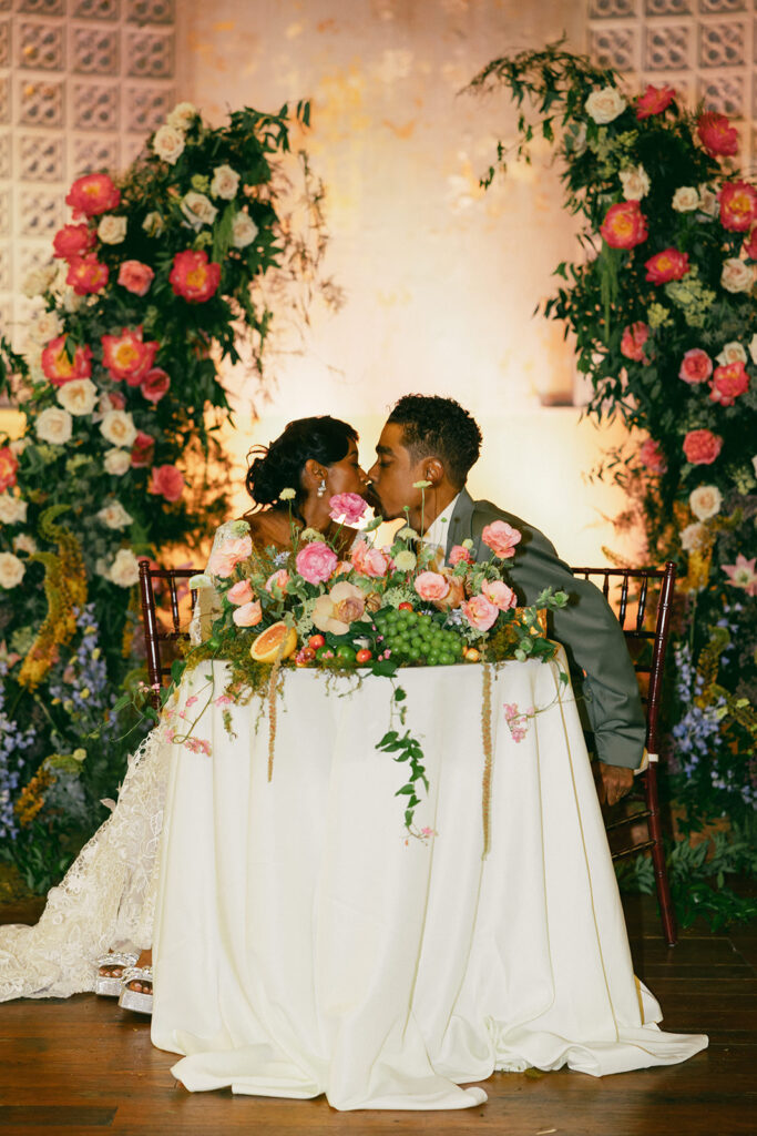 couple kisses under wedding floral decor at Hotel Peter and Paul New Orleans wedding
