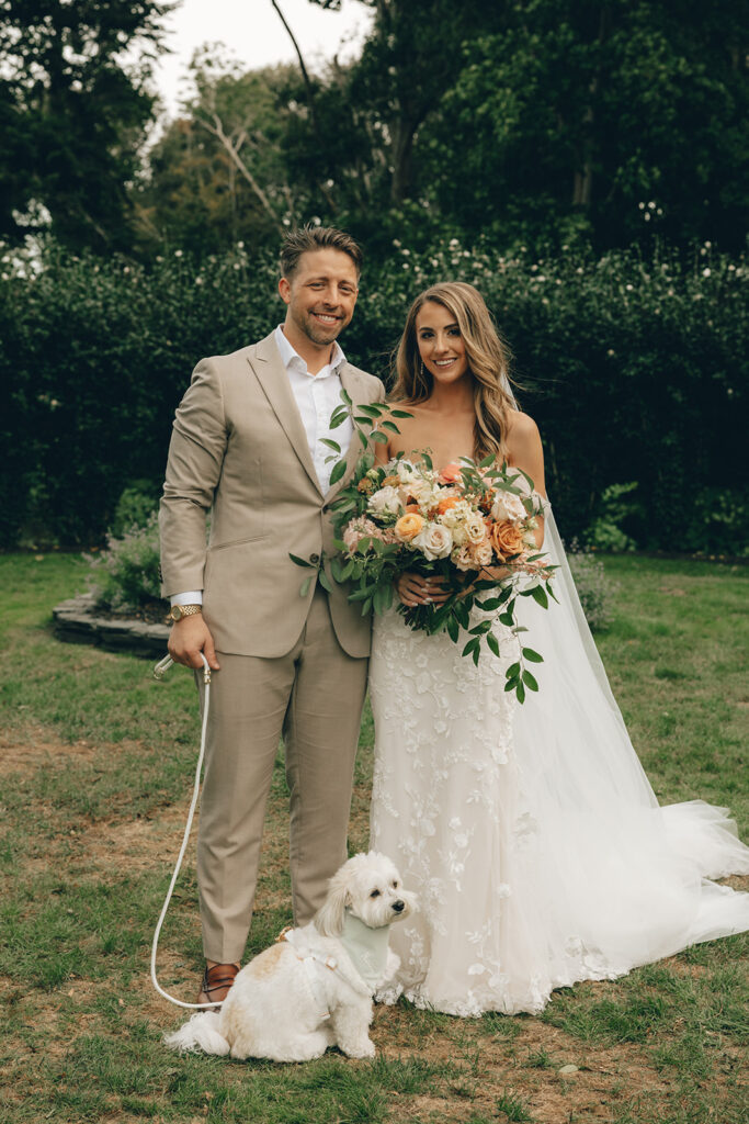 couple stands together with pet dog at wedding