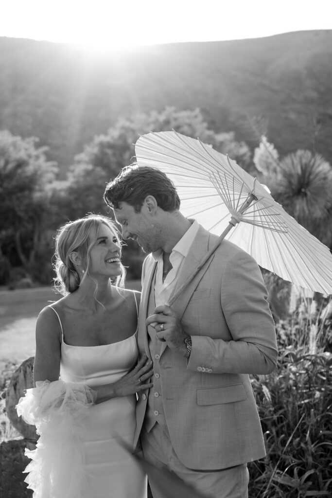 couple laughs under white parasol 