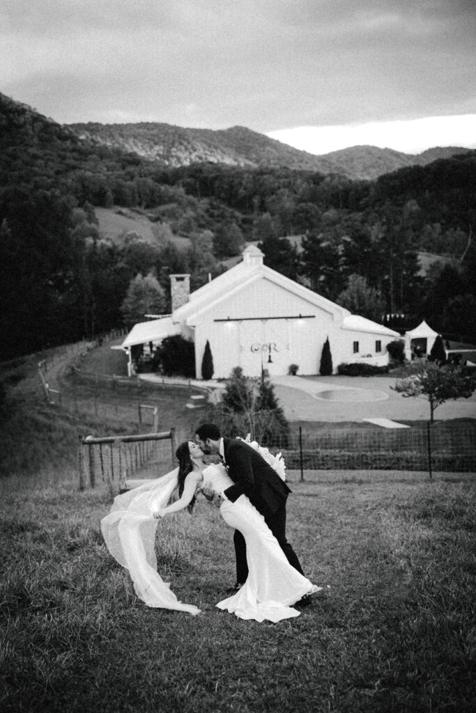 groom dipping bride with veil and view of mountains behind