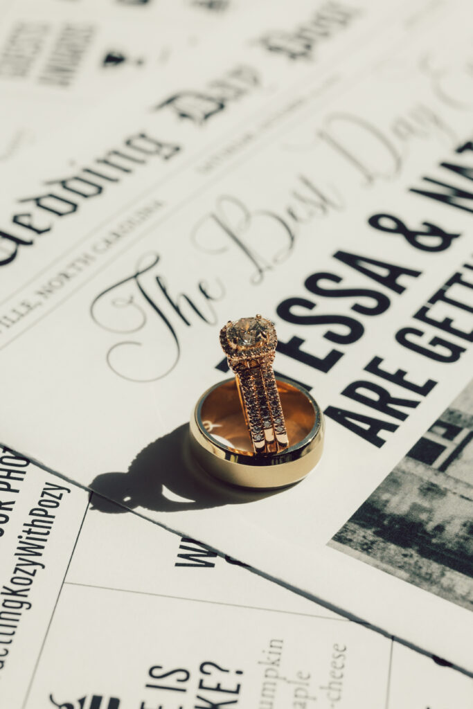 bride's engagement ring stacked inside groom's ring on top of a wedding newspaper
