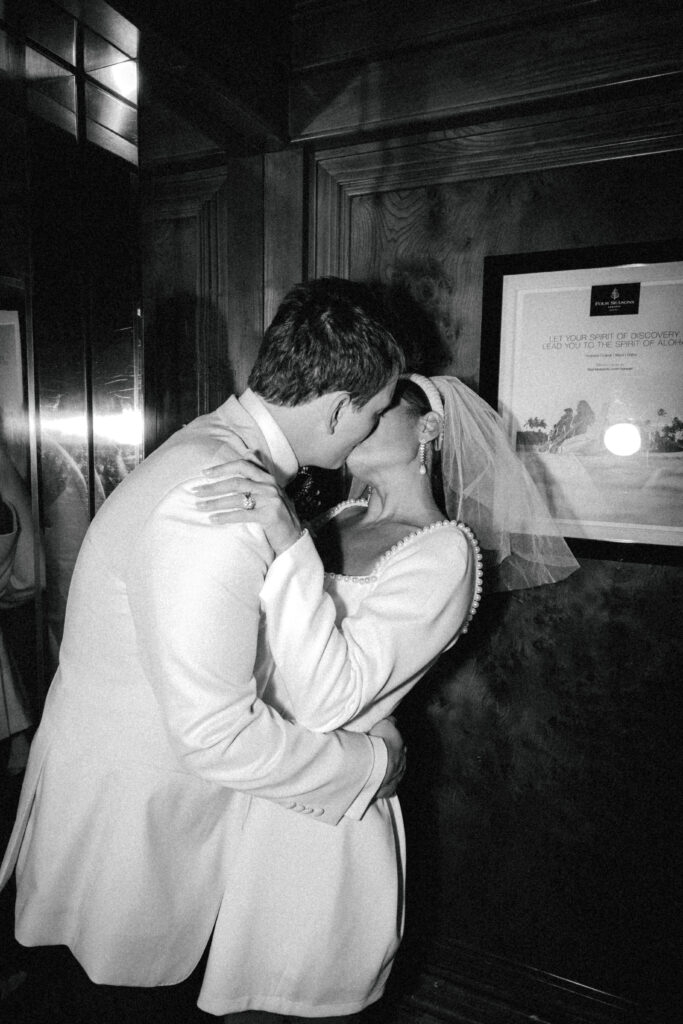 bride and groom kissing in elevator after bride changed outfits wearing short veil