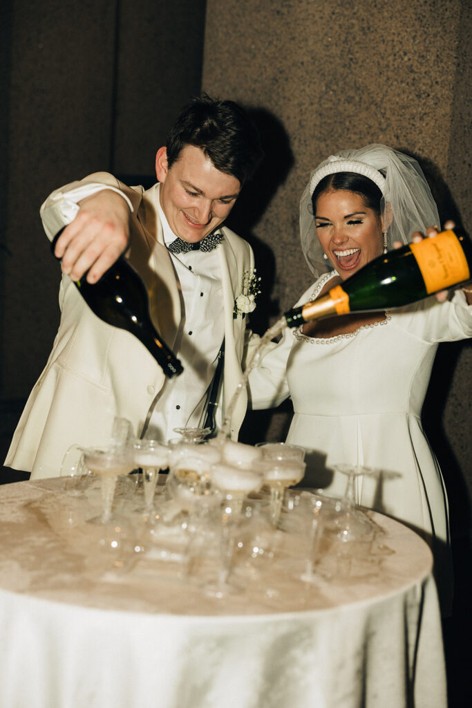 couple pours over champagne tower at wedding
