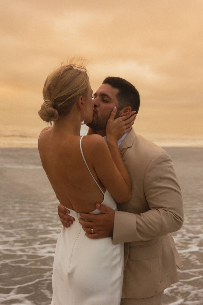 couple kisses at beach sunset wedding