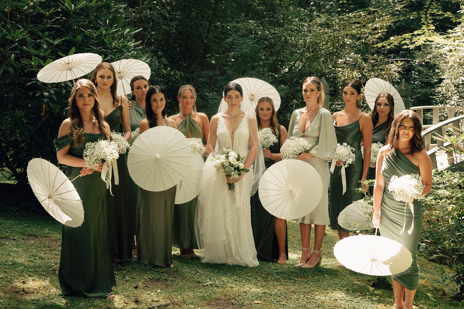 bride holds parasols with bridesmaids at outdoor wedding