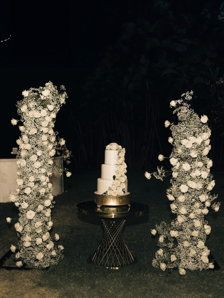white wedding cake surrounded by white flowers 