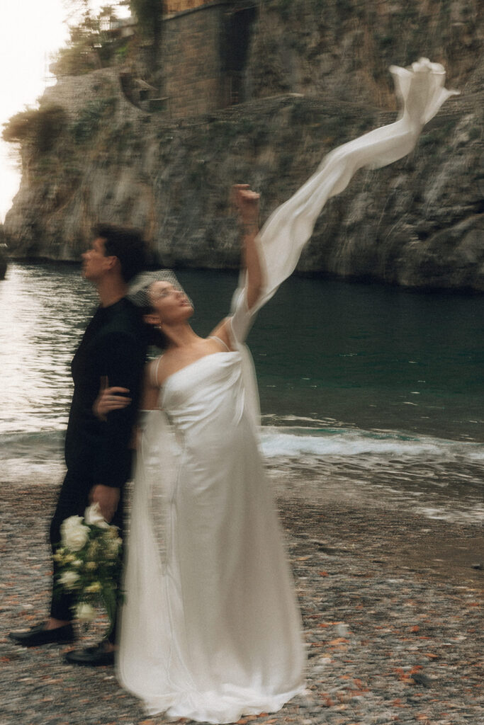 couple blows dress in the wind at Amalfi coast sunset elopement