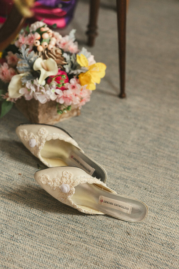white shoes on the ground beside wedding bouquet