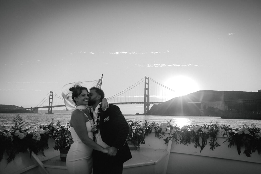 couple kisses on boat at San Francisco sunset wedding