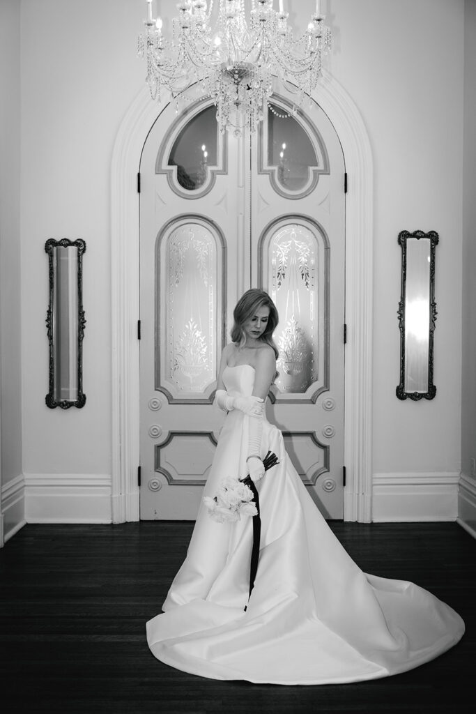 bride stands in front of grand doors at The Merrimon-Wynne House
