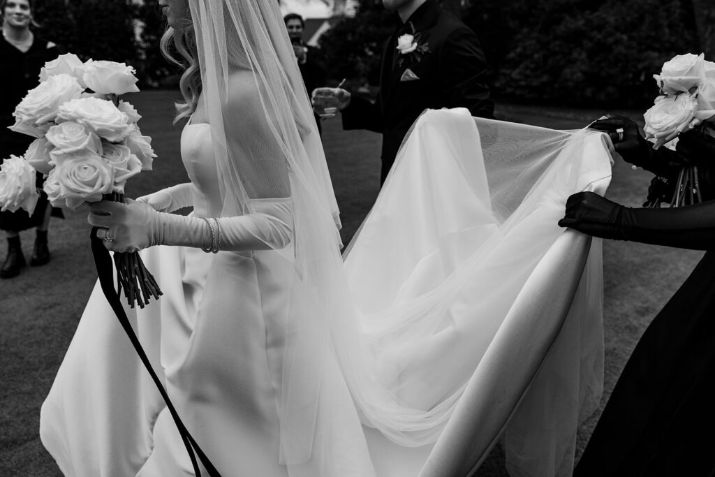 bridesmaids hold bride's wedding dress train 