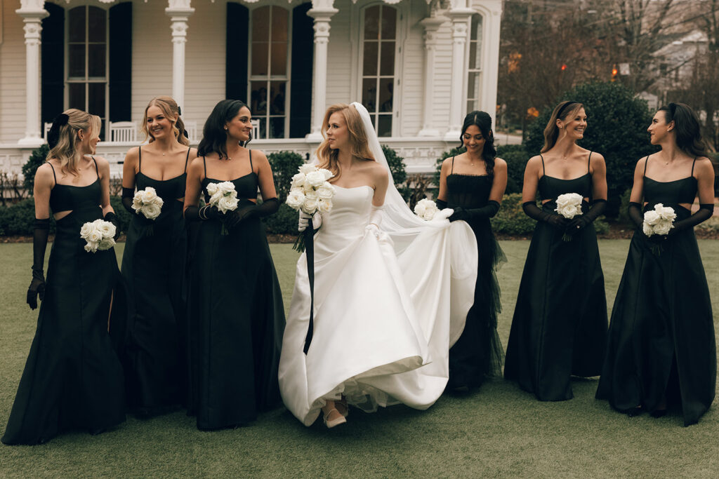 bride walks with bridesmaids along the grounds of The Merrimon-Wynne House