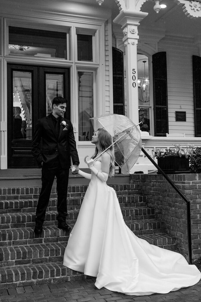 bride and groom stand holding hands in front of The Merrimon-Wynne House