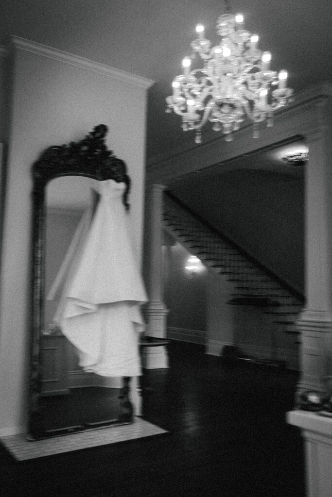 wedding dress hangs over mirror under chandelier at The Merrimon-Wynne House