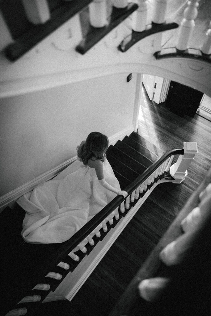 bride walks down staircase at The Merrimon-Wynne House