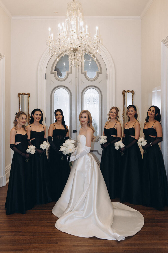 bride stands surrounded by bridesmaids holding white bouquets 