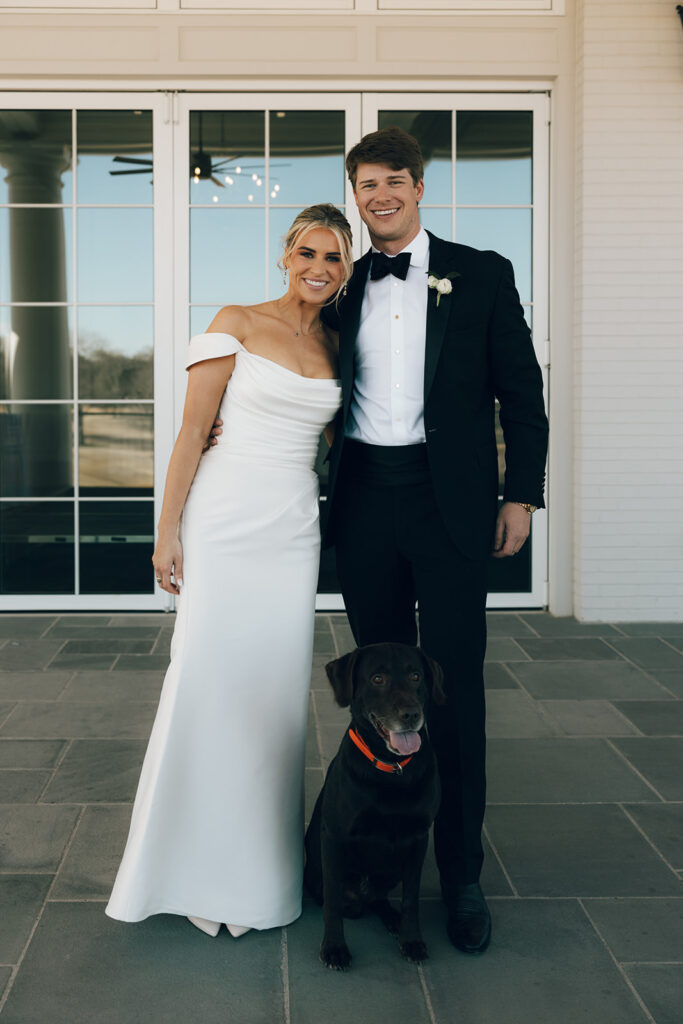 couple poses with pet dog on wedding day 