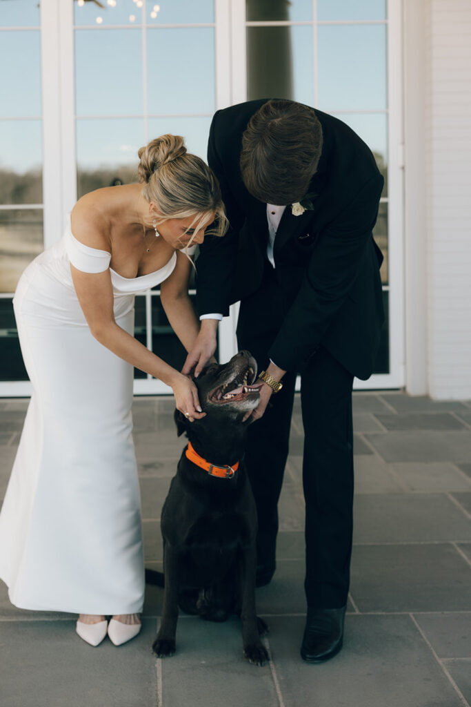 couple poses with pet dog on wedding day 