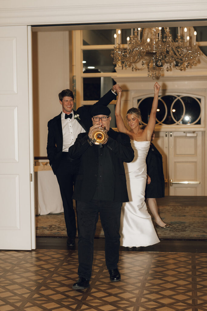 trumpet player leads couple into wedding reception 