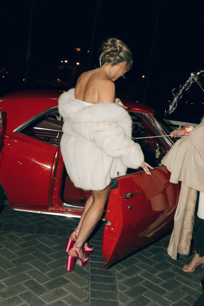 bride gets in red getaway car at wedding reception
